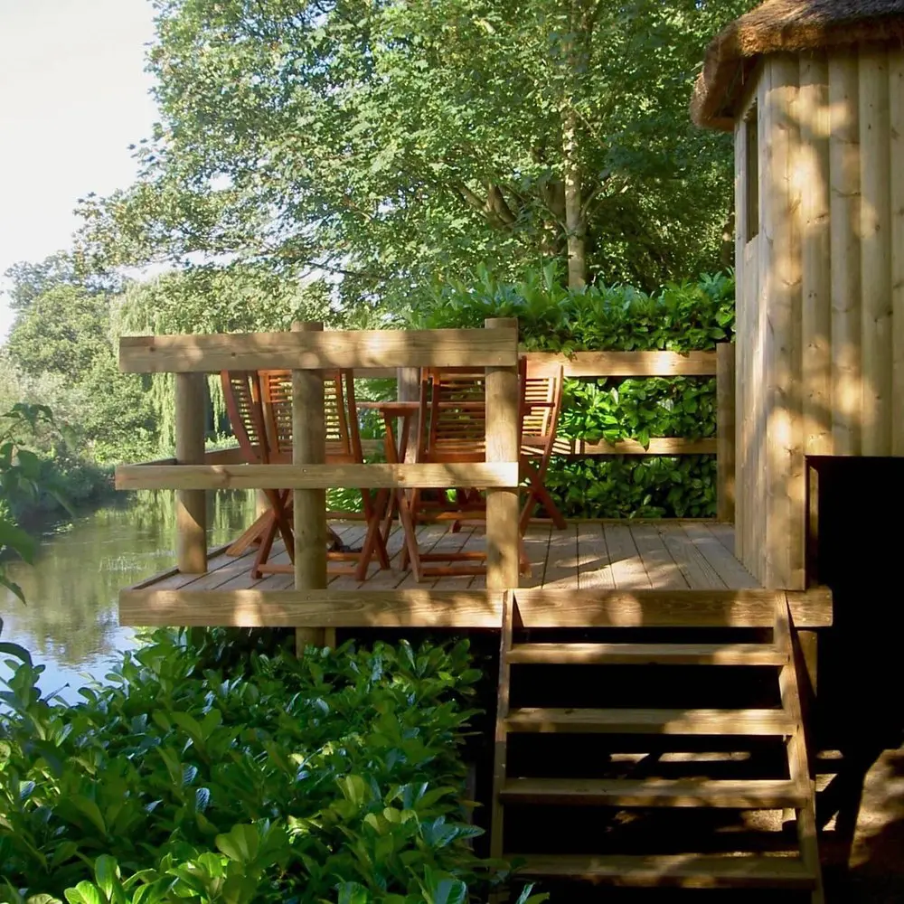 View of family deck platform alongside river and attached to kids play-house Treehouse.