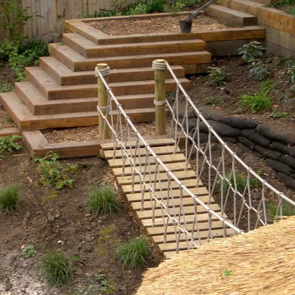 Rope Bridge in landscaped garden leading down from garden steps and into a kids Treehouse.