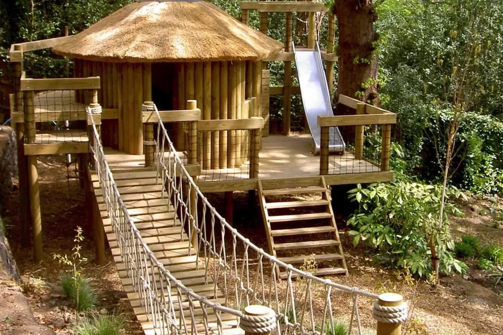 Treehouse in landscaped garden with deck, Slide long Rope Bridge and thatched roof.
