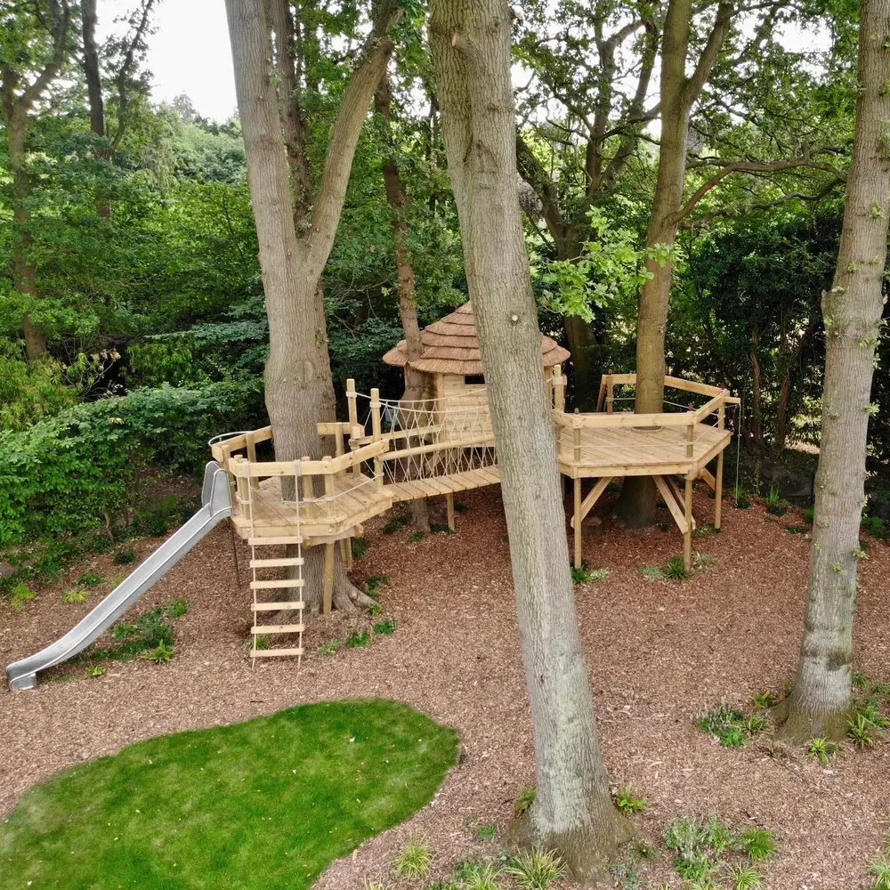 Treehouse set in garden woodland with Decks that wrap trees and linking Rope Bridge.