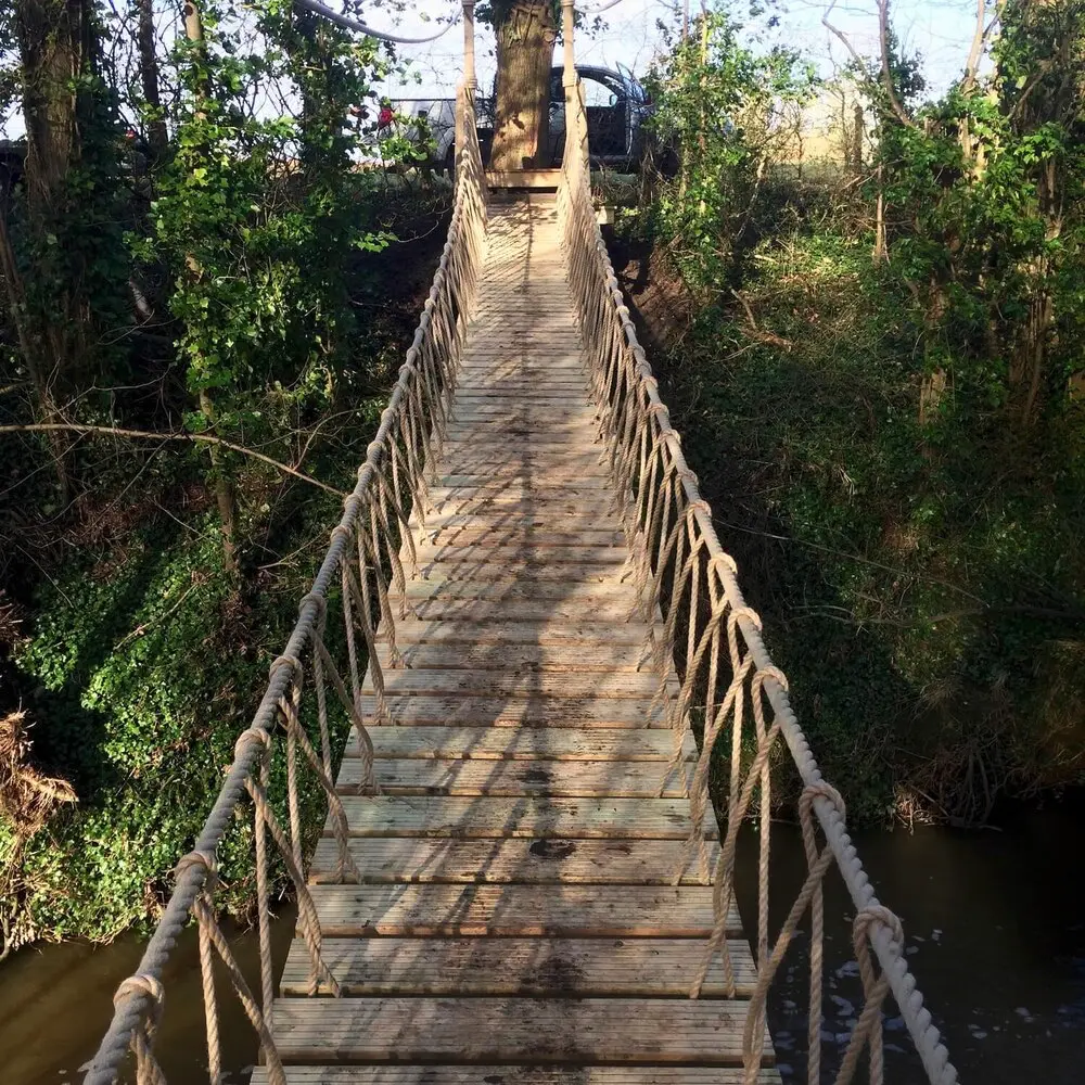 Rope Bridge spanning a river and leading into trees on the river bank.