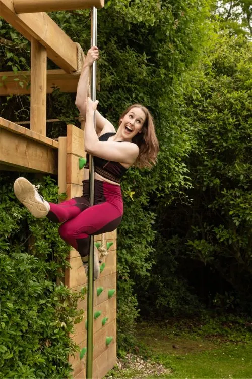 Woman sliding down a Fireman's Pole from, a Treehouse Deck Platform.