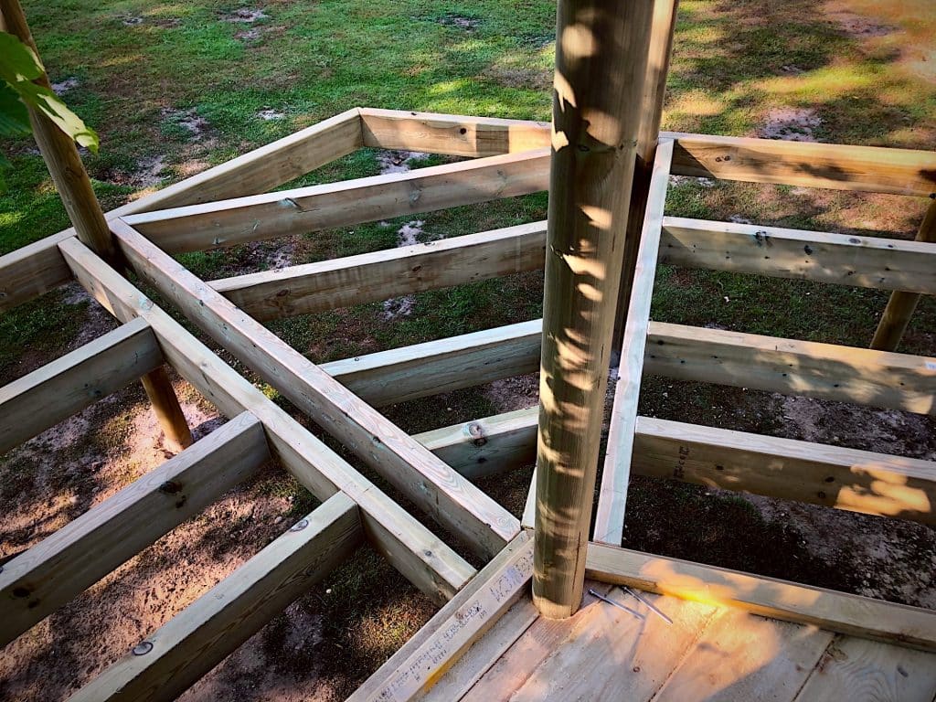 Picture shows a treehouse base under construction. There are three sections joined together in the picture and two large screws.